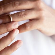 Close-up of hands removing a wedding ring, symbolizing divorce or separation.